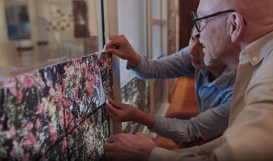Two gentlemen placing printed artwork on window
